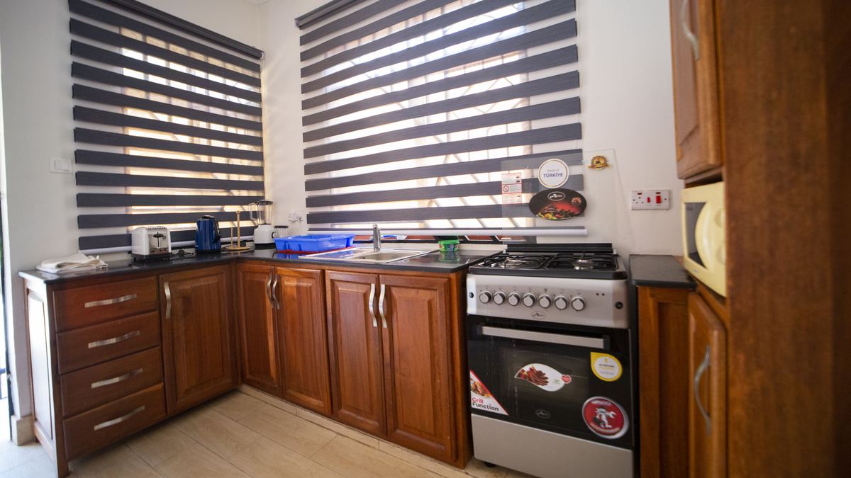 Private kitchen with wooden cabinets, cooker and microwave