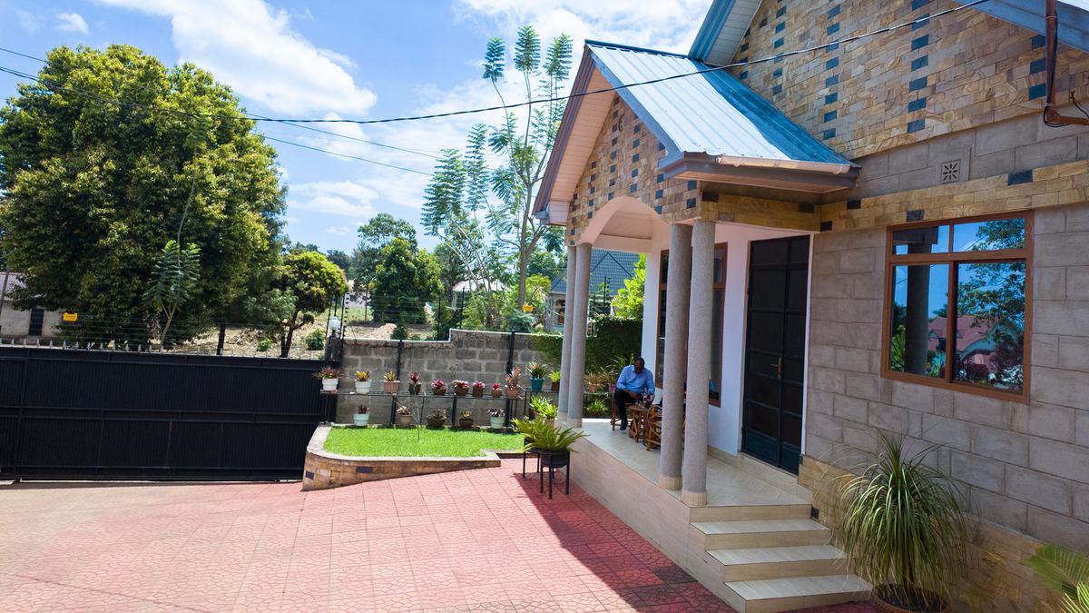 Pillared porch of the apartment beside a paved yard and lawn