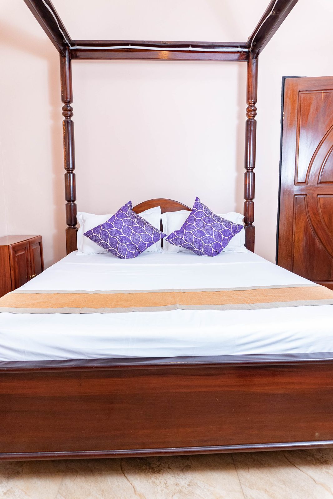 Four-poster bed with purple cushions