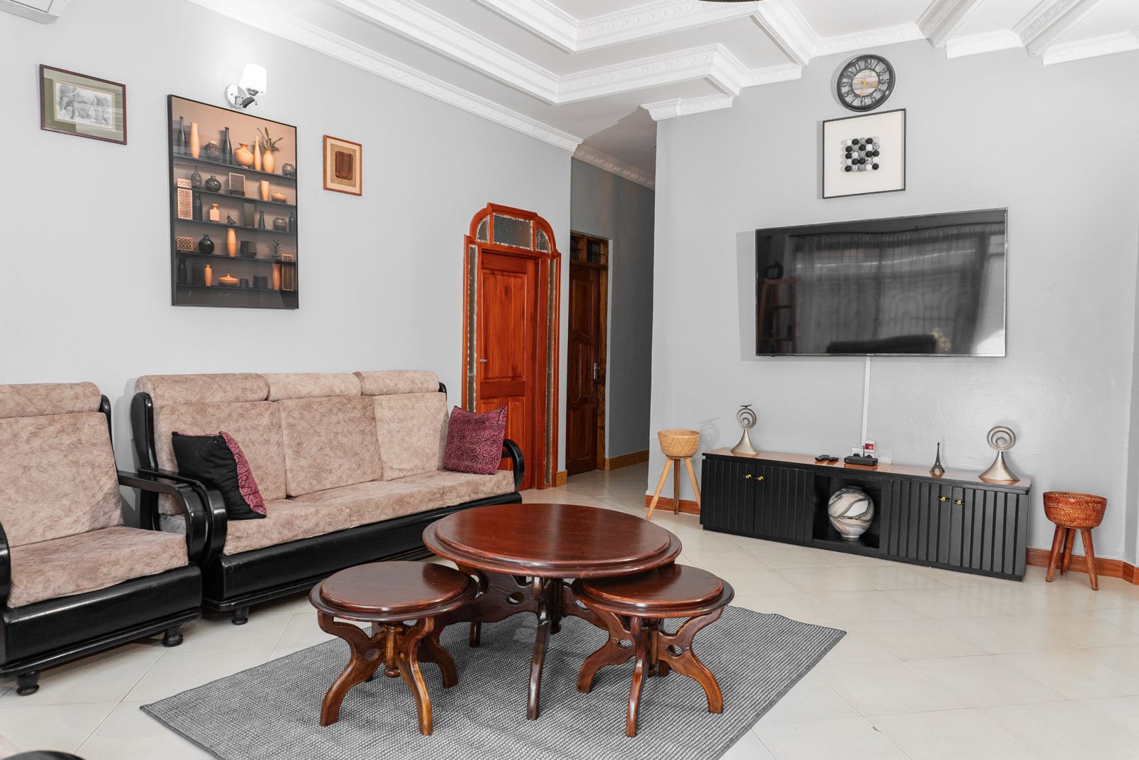 Guest lounge with sofas, wooden coffee table and TV at JJ Tanzania Homes lodge
