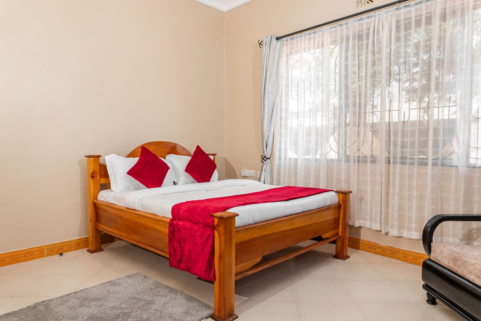 Double bedroom with red throw and hardwood bed at JJ Tanzania Homes lodge